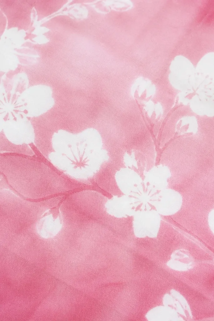 A pink wash background with blossoms that have bright white outlines and centers. The branch is visible as a faint line. White areas look like they were protected before dyeing.